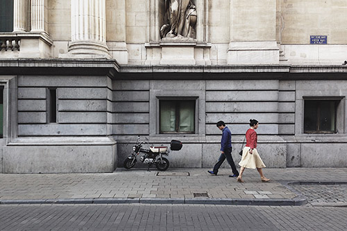 two people walking opposite direction street